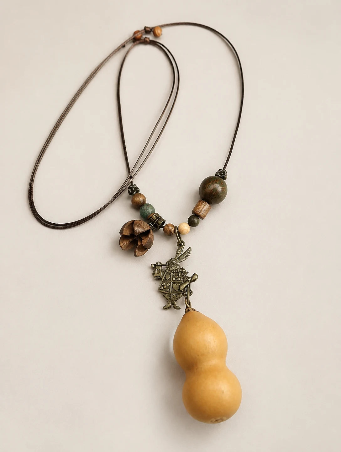 Golden Gourd-Silhouette Necklace — complete product view on a warm ivory background