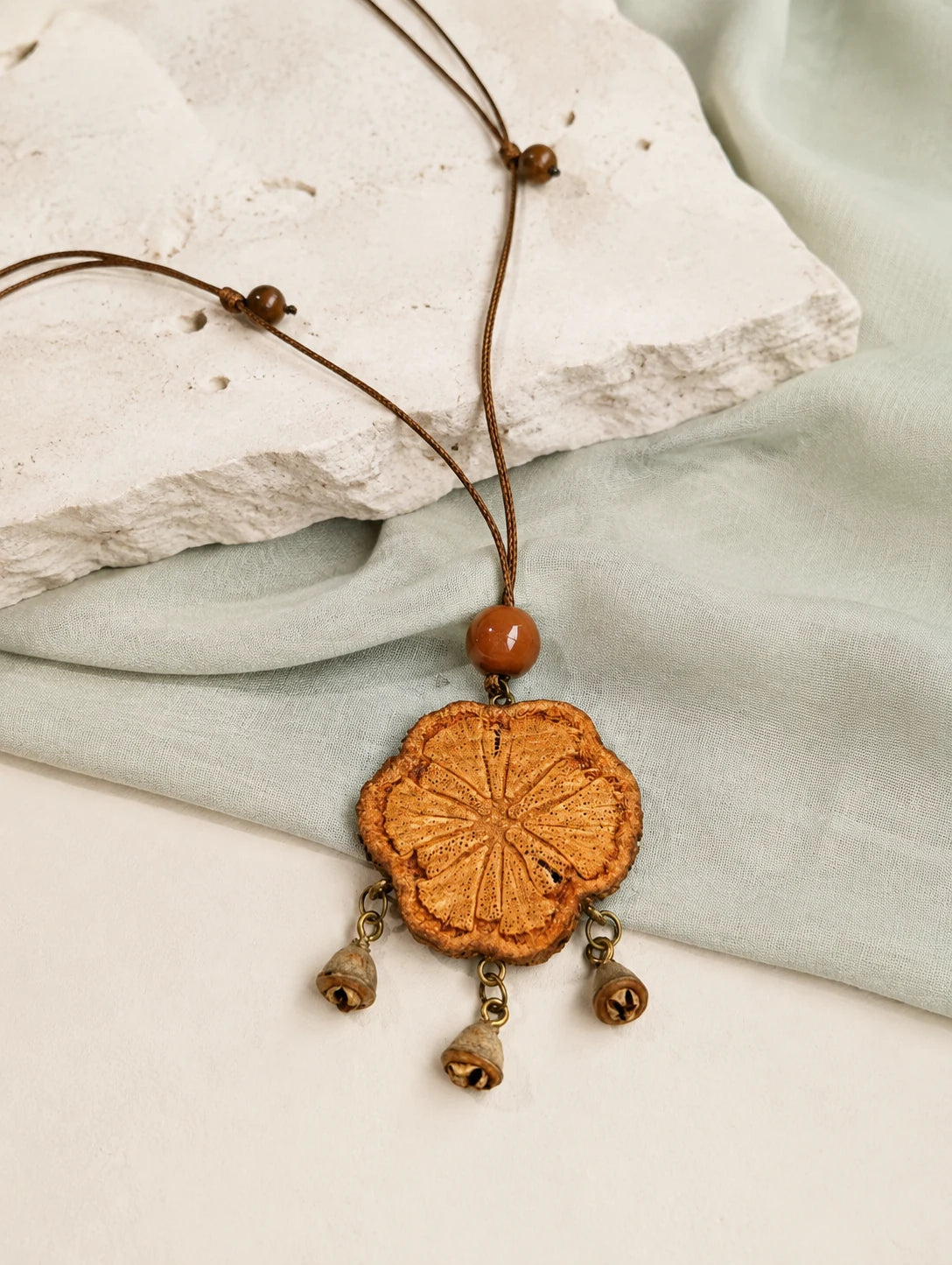 Carved Wood Tassel Necklace — restrained editorial still life