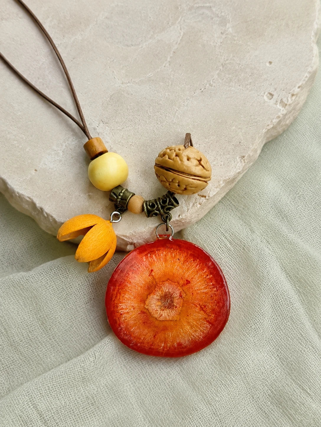 Deep Orange Slice Necklace — restrained editorial still life