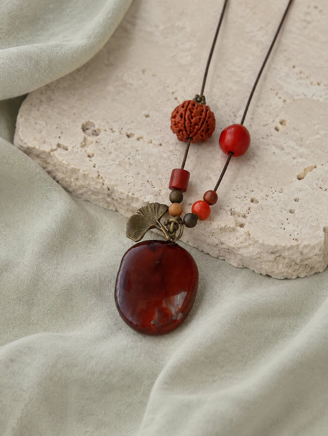 Deep Red Seed Pendant Necklace — restrained editorial still life