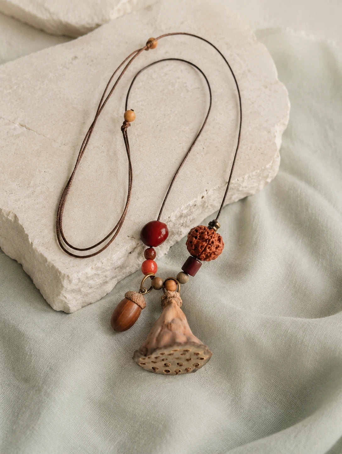 Fan Pod and Acorn Necklace — restrained editorial still life