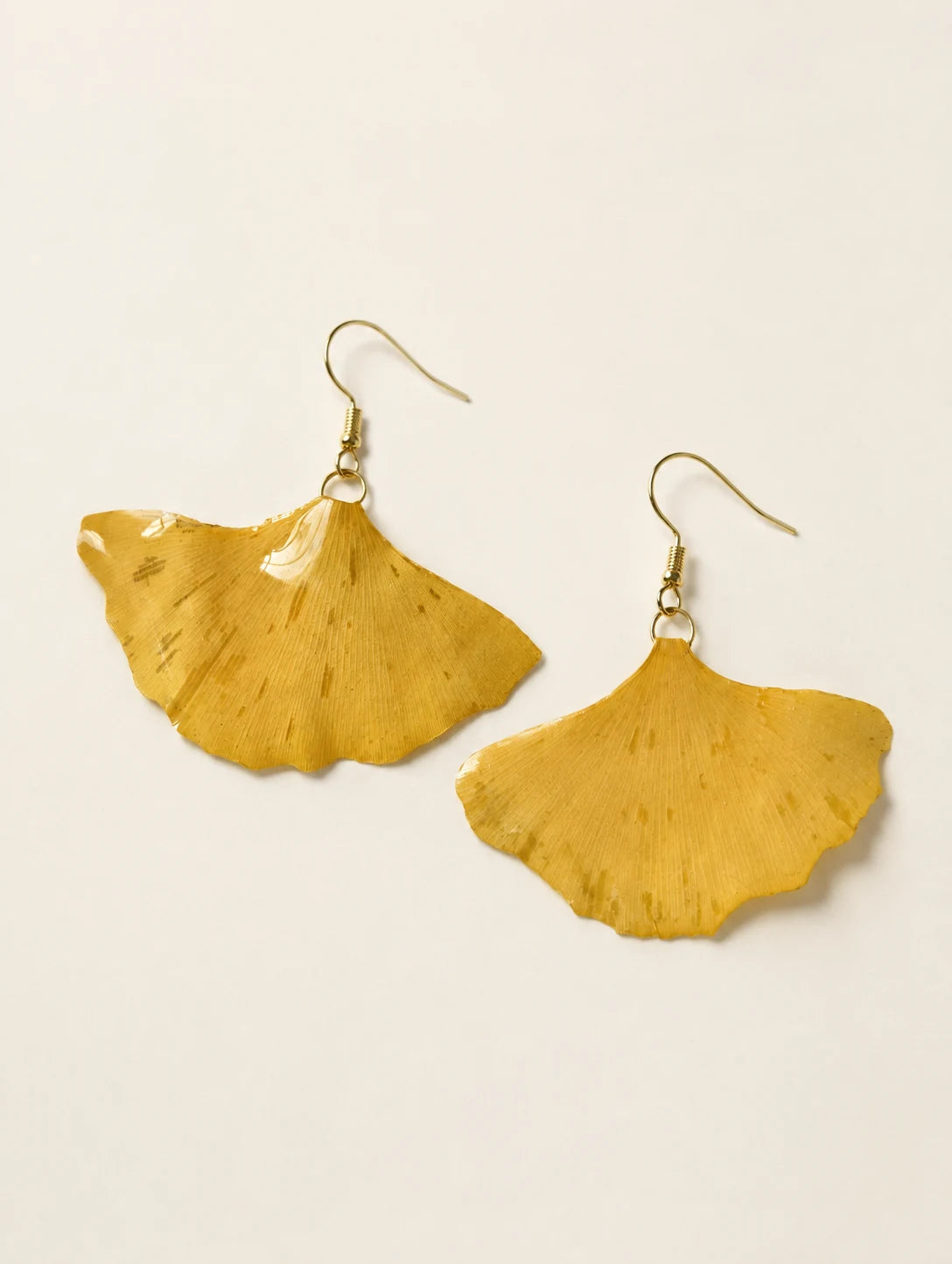 Golden Fan Leaf Drop Earrings — complete product view on a warm ivory background