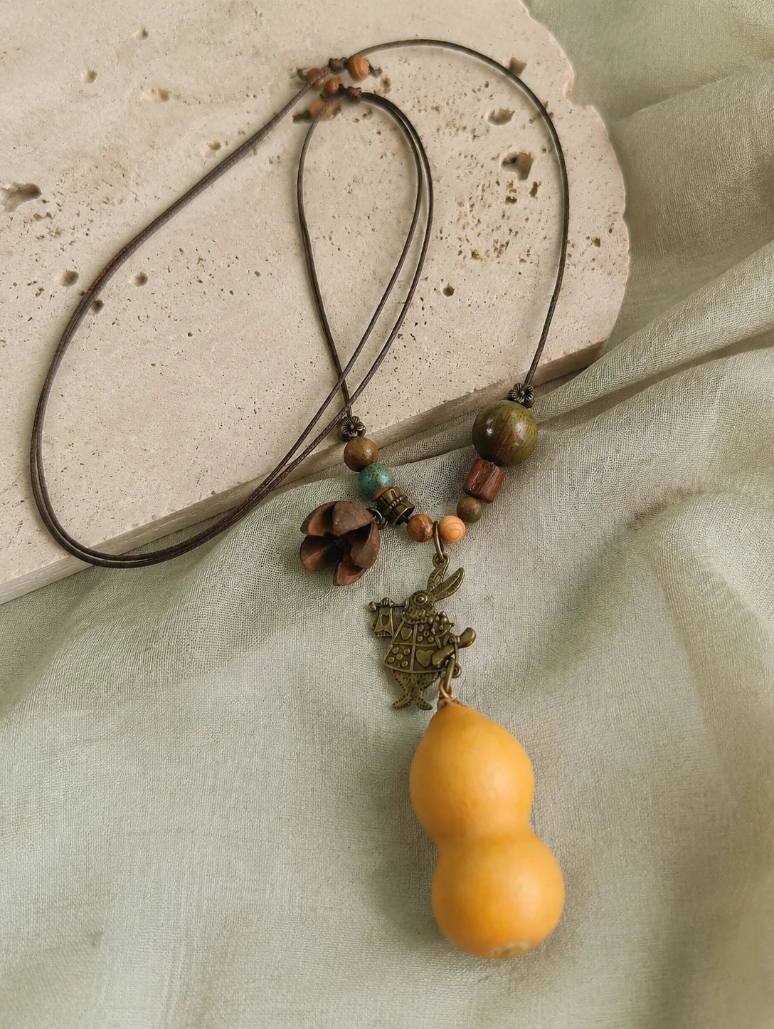 Golden Gourd-Silhouette Necklace — restrained editorial still life
