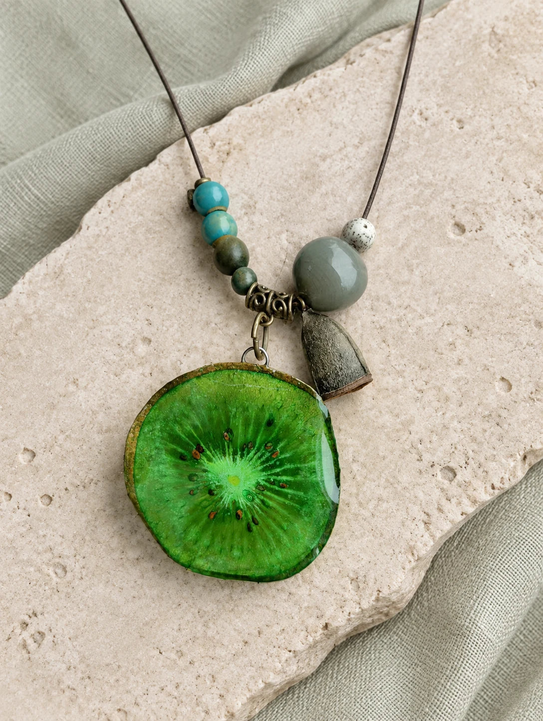 Green Slice and Bead Necklace — restrained editorial still life
