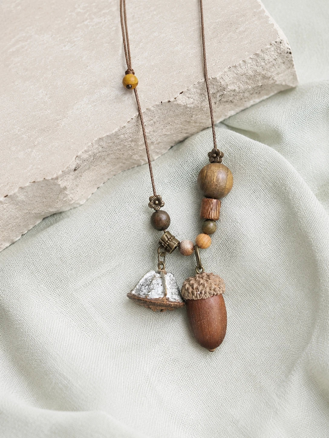 Long Acorn Cluster Necklace — restrained editorial still life