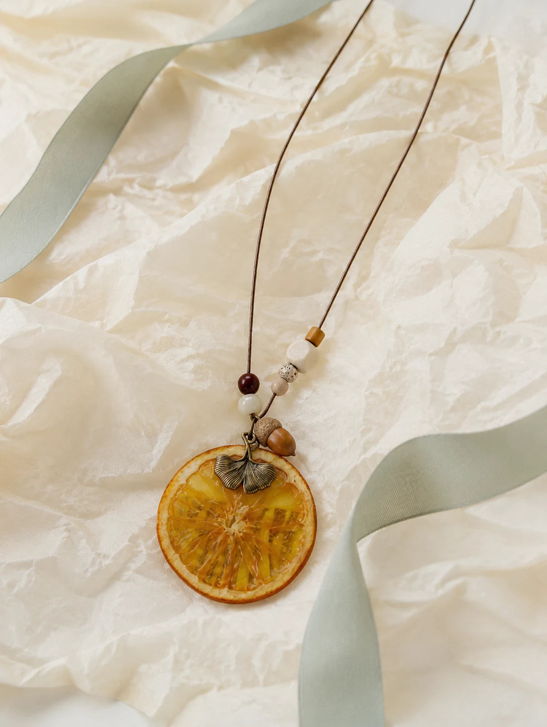 Orange Disc and Acorn Necklace — unbranded gift-context still life