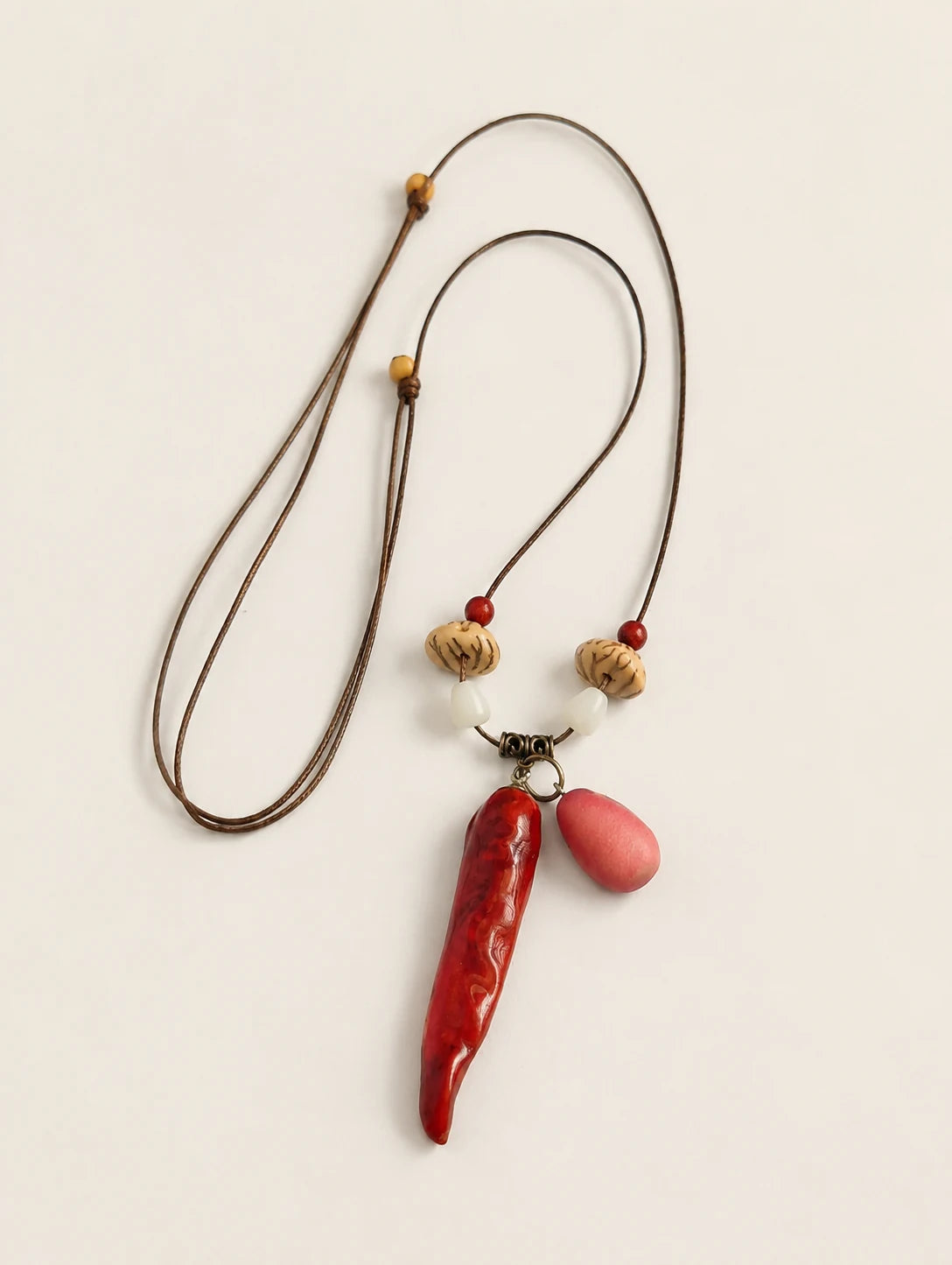 Red Pod and Bead Necklace — complete product view on a warm ivory background