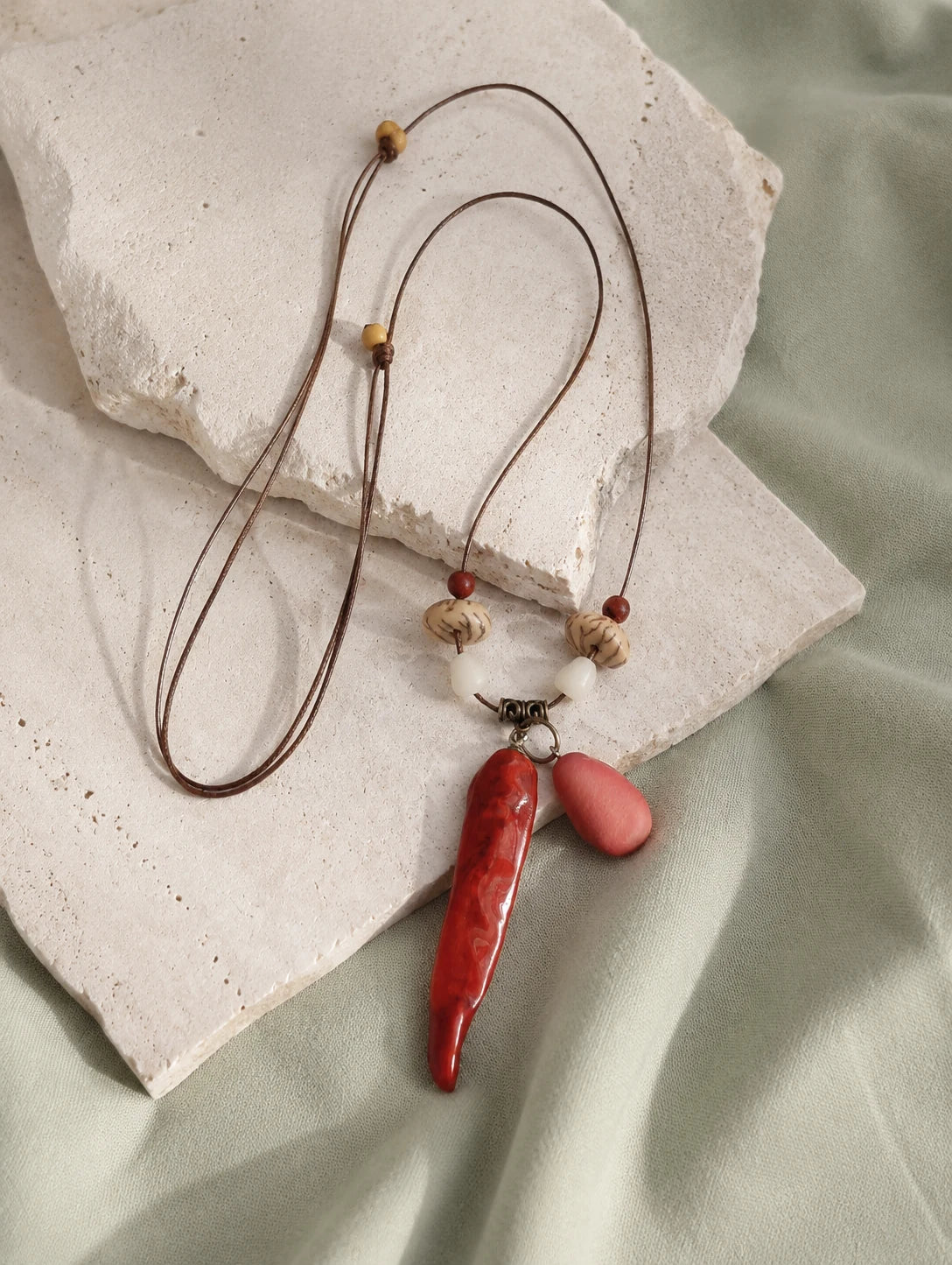 Red Pod and Bead Necklace — restrained editorial still life
