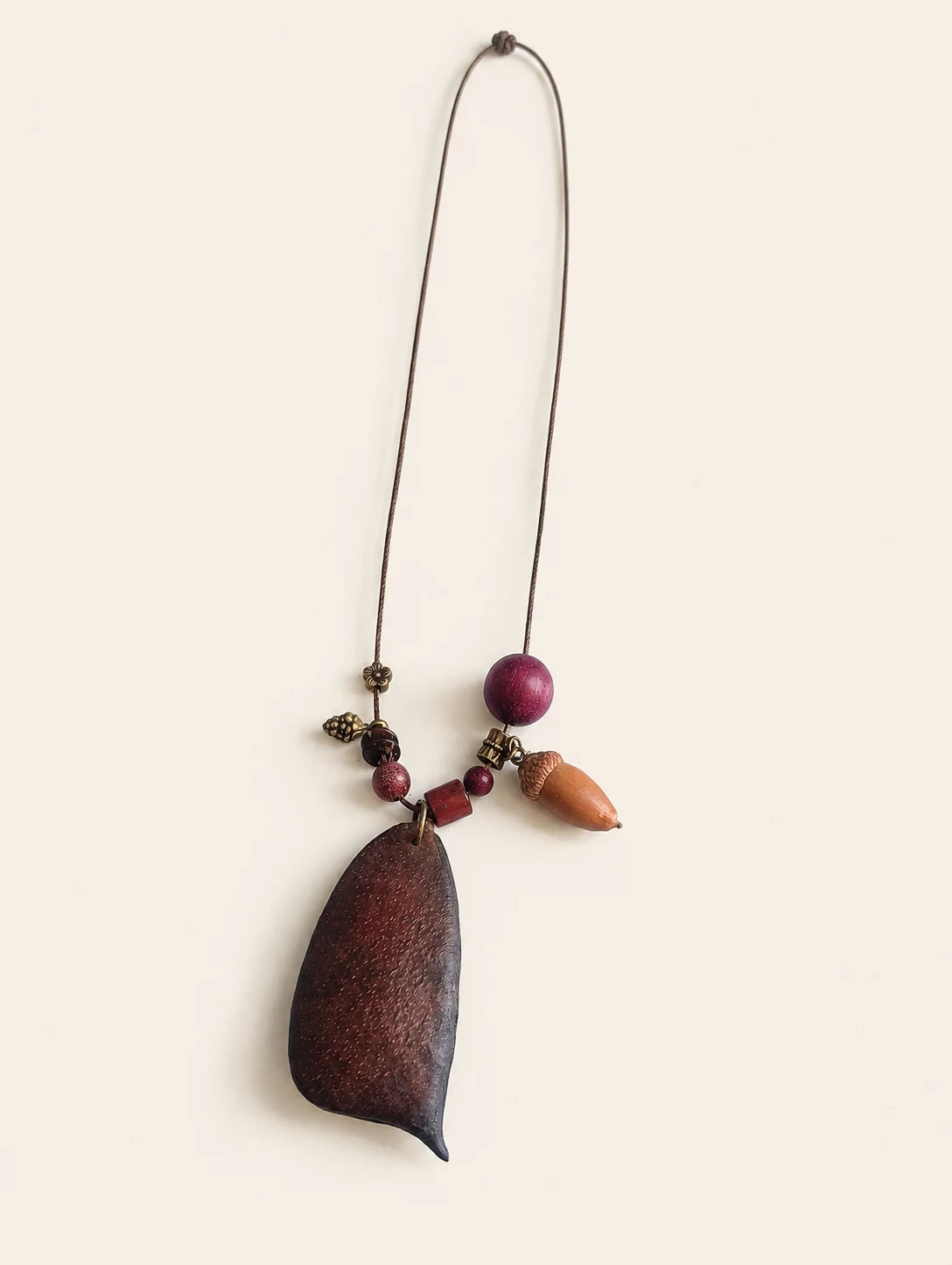 Seed Pod and Acorn Necklace — complete product view on a warm ivory background