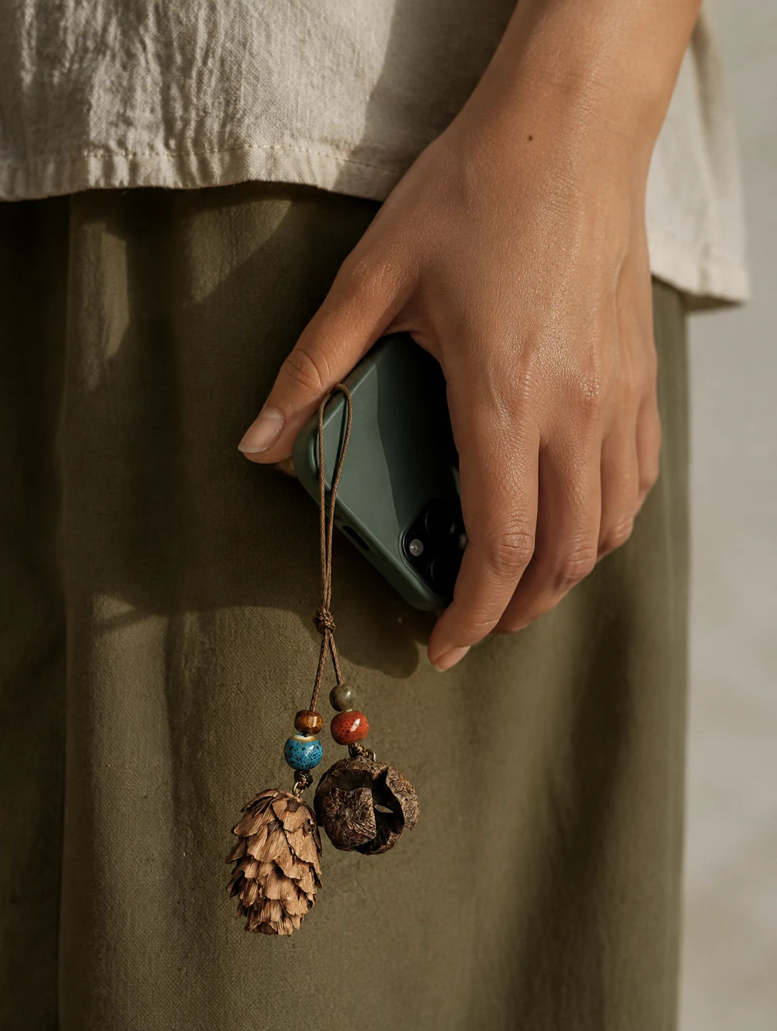 Model holding a phone with a woodland-inspired hanging charm