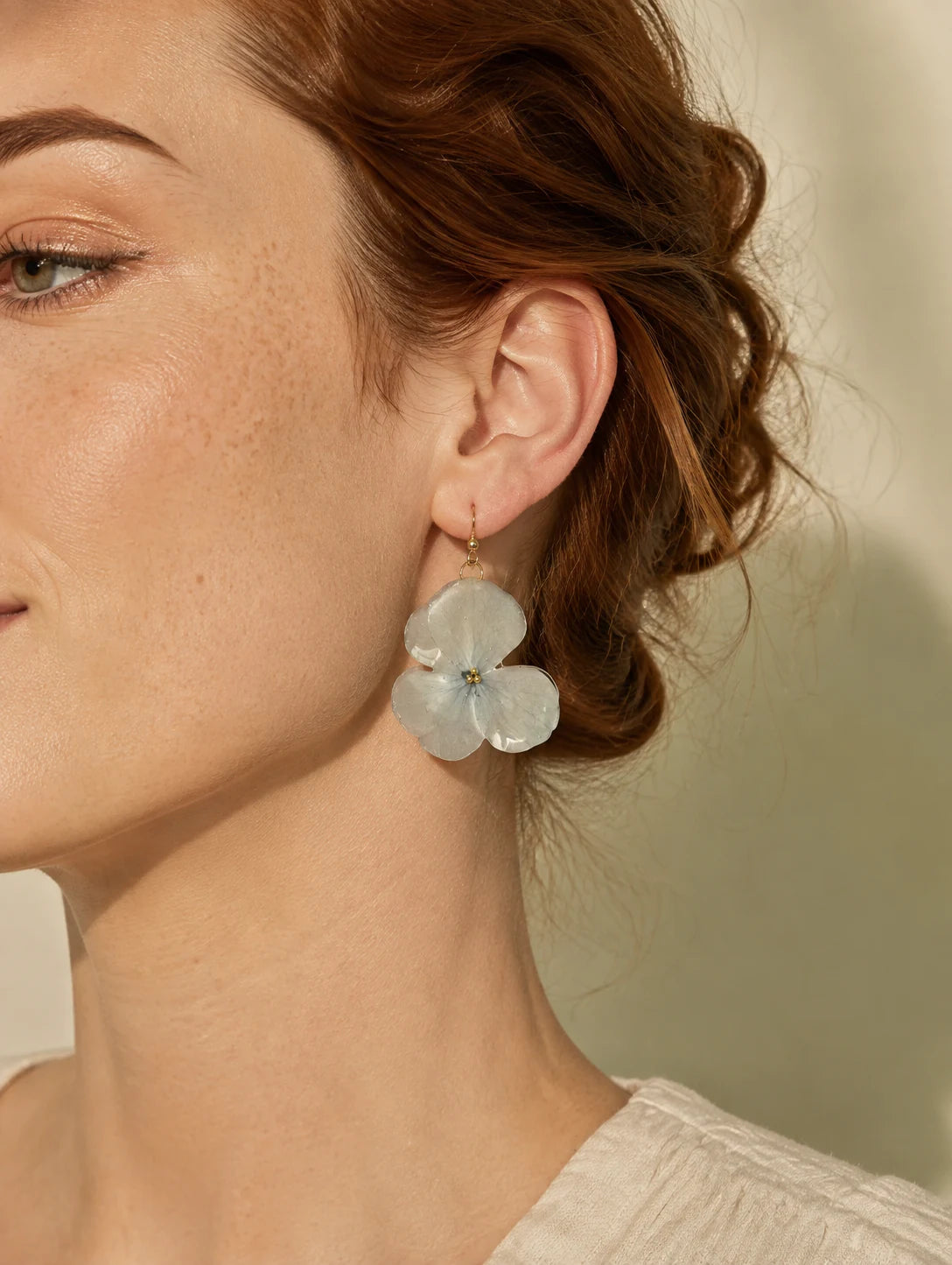 Model wearing pale blue botanical-inspired drop earrings