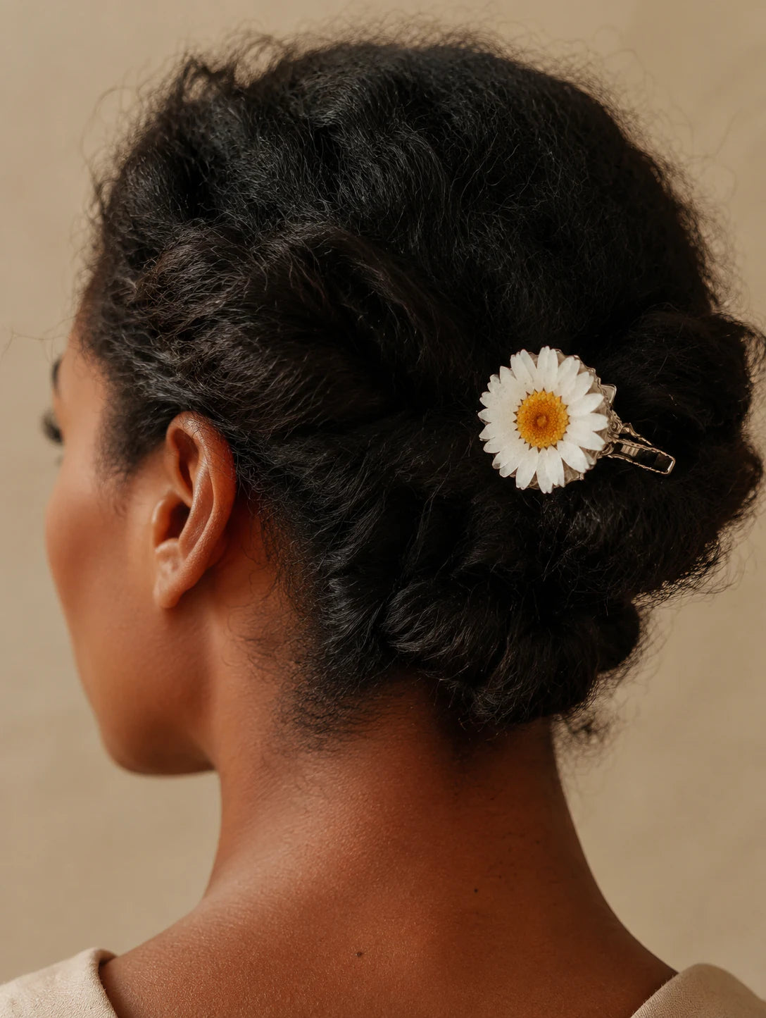Model wearing a white botanical-inspired hair clip in a low twist