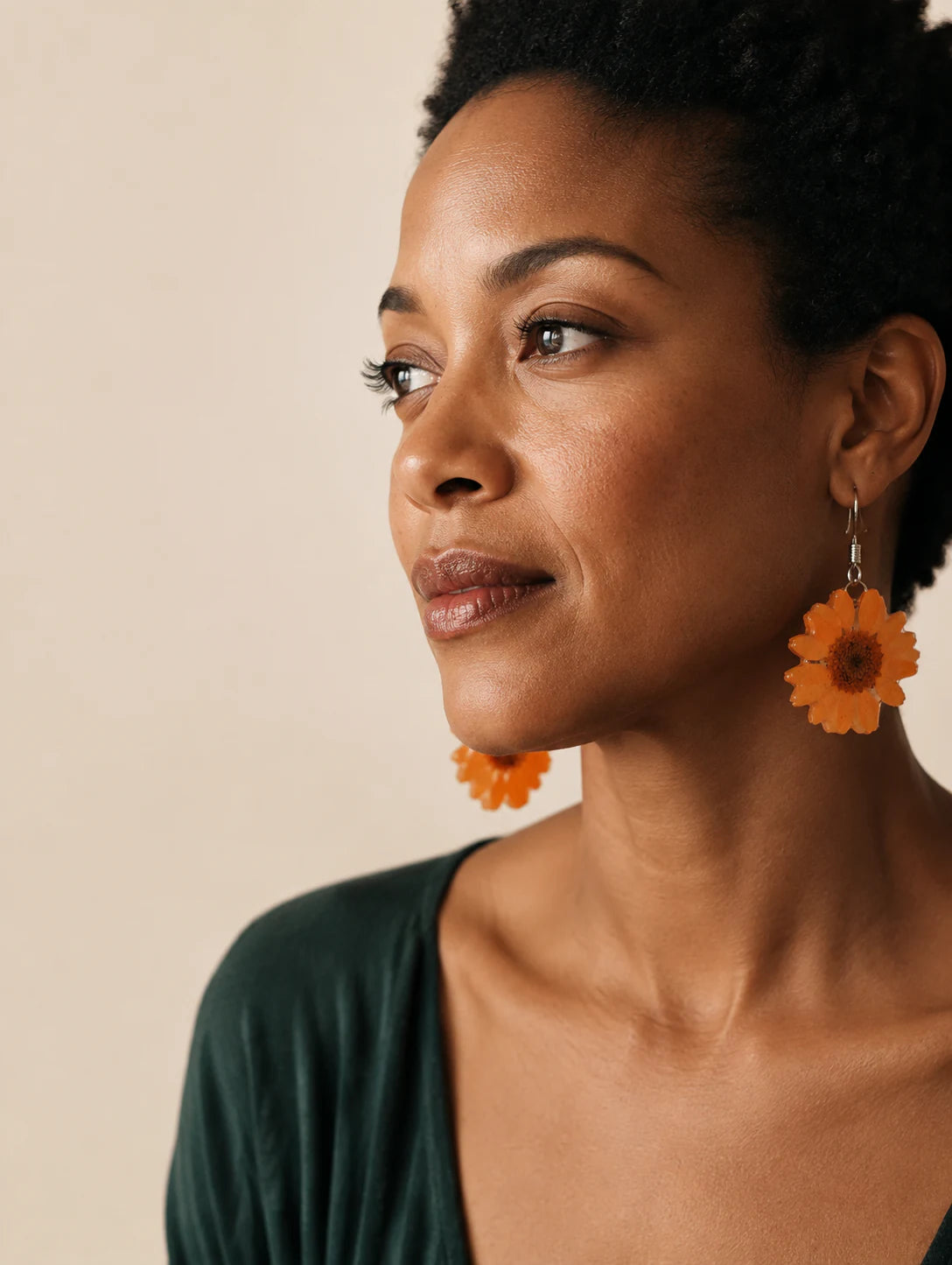 Model wearing orange botanical-inspired drop earrings in warm editorial light